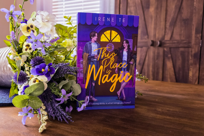 A paperback copy of This Place is Magic by Irene Te, displayed next to a bouquet of flowers